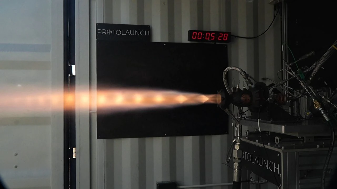 A rocket engine on a test stand firing an orange exhaust plume to the left.